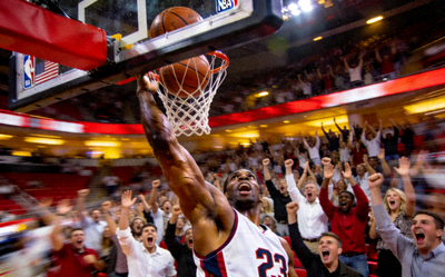 NBA比赛现场特写 - 球员高高跃起完成一记势大力沉的扣篮，观众席爆发出热烈欢呼